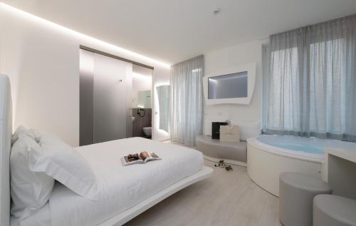 a white bedroom with a tub and a bed and a sink at AHD Rooms in Milan