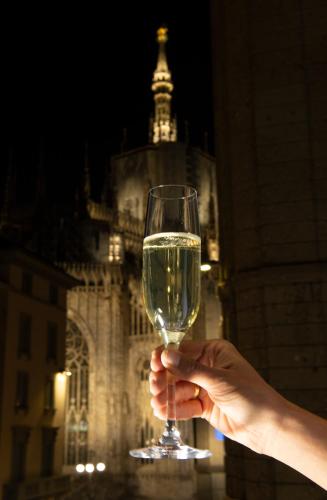 a person holding a glass of wine in front of a building at AHD Rooms in Milan