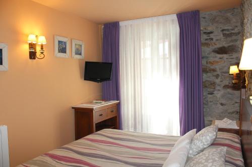 a bedroom with a bed and a television and a window at Hotel Casa Prendes in Cudillero