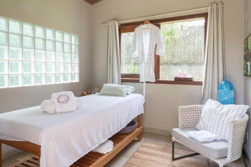 um quarto com uma cama, uma cadeira e uma janela em Casa da Lua Pousada em Alto Paraíso de Goiás