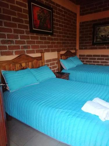 two blue beds in a bedroom with a brick wall at Villas victoria mirador in Zihuatanejo