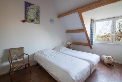 a bedroom with a bed and a chair and a window at Farm Overleekerhoeve in Monnickendam