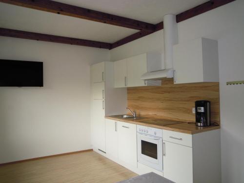 a kitchen with white cabinets and a tv on the wall at Ferienwohnungen Familie Jarnig Inge in Görtschach
