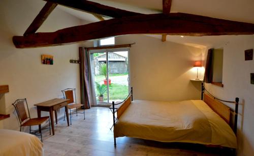 een slaapkamer met een bed, een tafel en een raam bij La Frapperie in La Pommeraie-sur-Sèvre