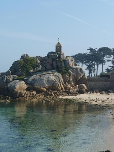 une petite île avec un phare sur une plage dans l'établissement Les crèches de Boiséon, à Penvénan