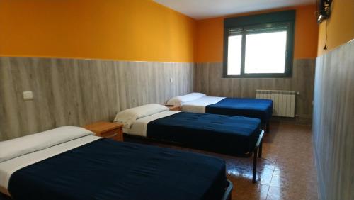 a room with three beds and a window at Hostal San Marcos II in Guadalajara