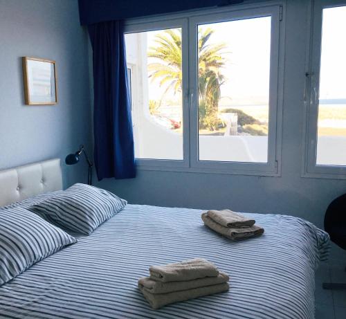 a bed with two towels on it with a window at EL Drago in Costa Teguise