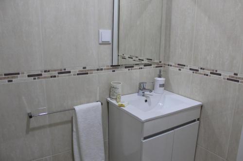 uma casa de banho branca com um lavatório e um espelho em University View Flat em Coimbra