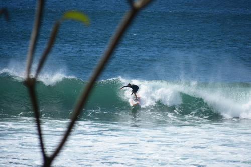 a man riding a wave on a surfboard in the ocean at Vibra Guesthouse Popoyo in Popoyo