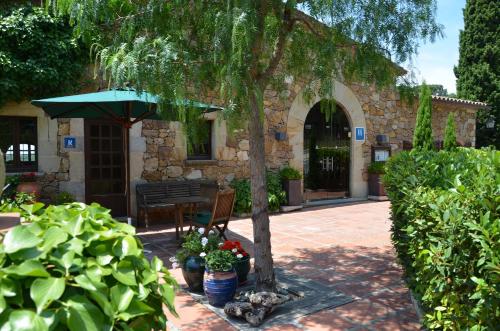 a patio with a tree and a table and umbrella at Hotel Galena Mas Comangau in Begur