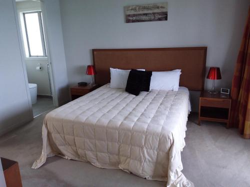 1 dormitorio con 1 cama grande con sábanas blancas y almohadas negras en Oceanfront Penthouse Bay of Islands NZ, en Paihia