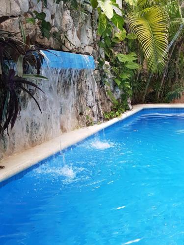 une cascade dans une piscine d'eau bleue dans l'établissement Hotel El Moro, à Puerto Morelos
