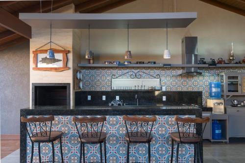 a kitchen with a counter with bar stools at Casa Temporada Castro Alves in Bonito