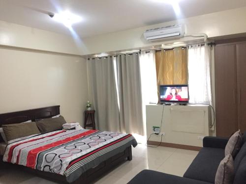a bedroom with a bed and a tv and a couch at Love This Place in Manila