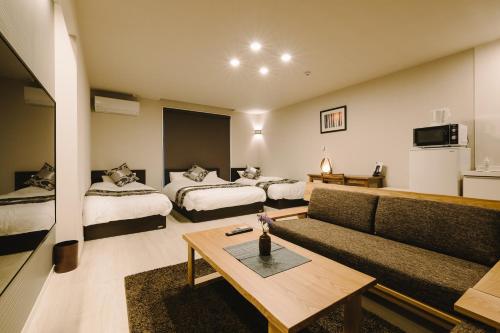 uma sala de estar com duas camas e um sofá em GRAND BASE Karatsu Ekiminami em Karatsu