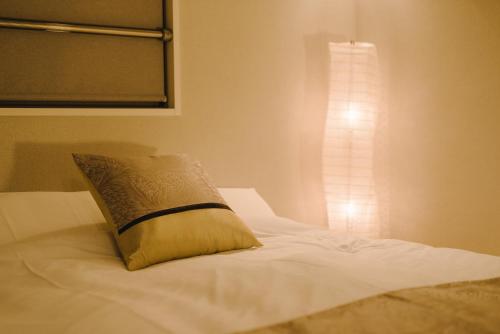 a bed with a pillow on it with a window at GRAND BASE Karatsu Ekiminami in Karatsu
