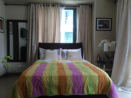 a bedroom with a colorful bed and a window at Love This Place in Manila
