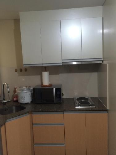 a kitchen with white cabinets and a microwave at Love This Place in Manila