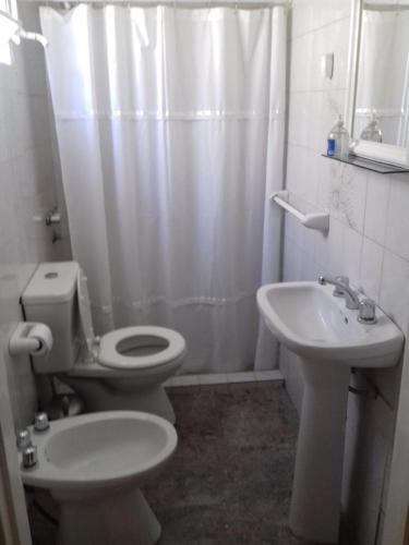 a white bathroom with a toilet and a sink at EL DESCANSO DEPARTAMENTOS in Neuquén