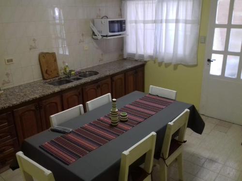 a kitchen with a black table and chairs and a kitchen with a microwave at EL DESCANSO DEPARTAMENTOS in Neuquén