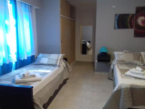 a bedroom with two beds in a room with a window at EL DESCANSO DEPARTAMENTOS in Neuquén