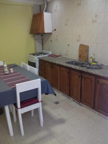 - une cuisine avec une table, une cuisinière et un évier dans l'établissement EL DESCANSO DEPARTAMENTOS, à Neuquén