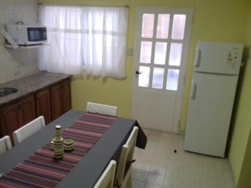 een keuken met een tafel en een witte koelkast bij EL DESCANSO DEPARTAMENTOS in Neuquén