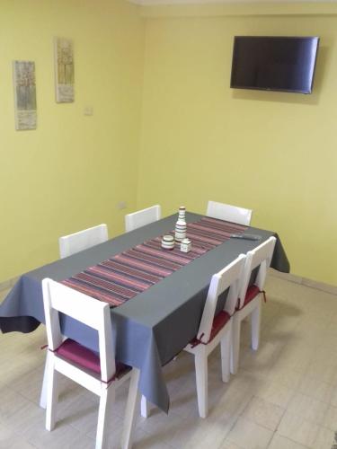 een eettafel met witte stoelen en een blauwe tafel en een televisie bij EL DESCANSO DEPARTAMENTOS in Neuquén