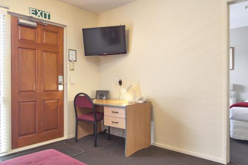 a room with a desk and a television on a wall at Apollo Motel in Christchurch