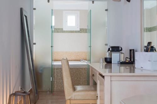 a bathroom with a tub and a desk with a chair at Lagos Mare Hotel in Agios Prokopios