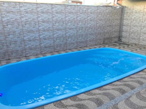 uma piscina azul em frente a uma parede de tijolos em Casa temporada Aroeira em Olímpia