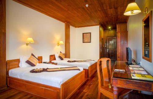 two beds in a room with a desk and a computer at Ta Prohm Hotel & Spa in Siem Reap