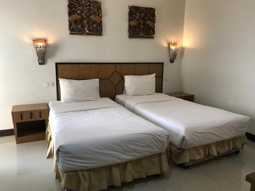 two beds in a hotel room with white sheets at UD Residence in Udon Thani