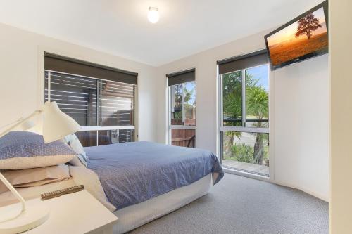 a bedroom with a bed and large windows at Lake House in Lake Tyers