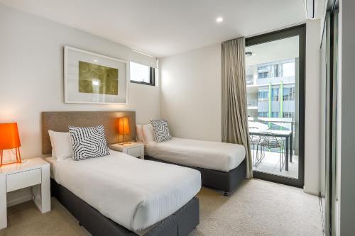 ブリスベンにあるVine Apartments South Brisbaneのベッド2台とバルコニー付きのホテルの部屋