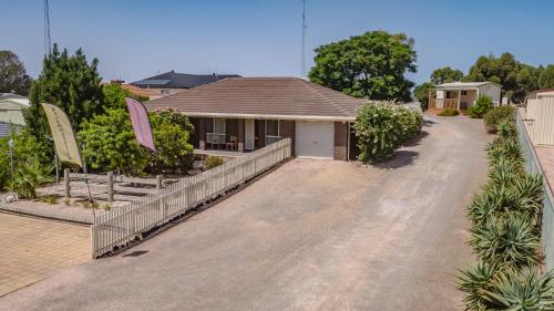 a house with a fence in front of a driveway at Moonta Bay Accommodation in Port Moonta