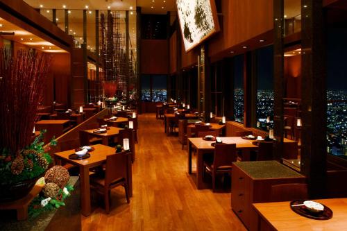 a restaurant with tables and chairs with a view of the city at Park Hyatt Tokyo in Tokyo