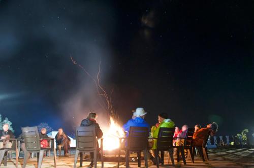 a group of people sitting around a fire at night at Rakkh Resort, a member of Radisson Individuals Retreats in Pālampur
