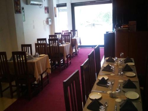 jadalnia ze stołami i krzesłami oraz dużym oknem w obiekcie Creek Hotel w mieście Panaji
