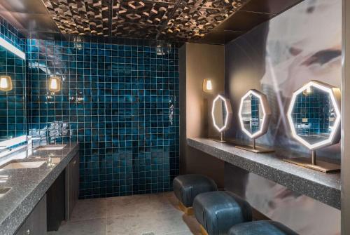 a bathroom with two sinks and mirrors and blue tiles at TRYP by Wyndham Newark Downtown in Newark