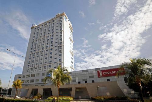a tall white building with palm trees in front of it at TRYP by Wyndham Mall of Asia Manila in Manila