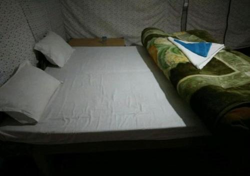 a bed with a white sheet and pillows on it at The Buddha Camp - Pangng in Spangmik
