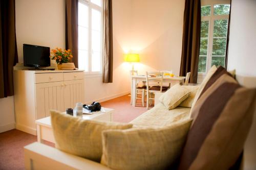 a living room with a couch and a table with a television at Résidence Goélia Les Portes d'Étretat in Maniquerville