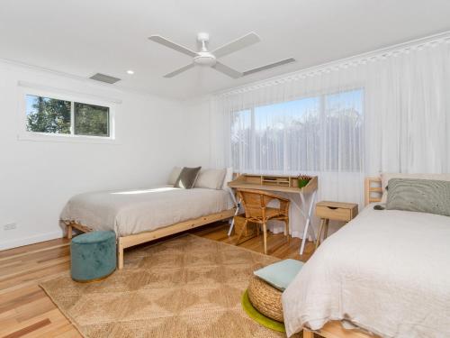 a bedroom with two beds and a desk and a window at Marine Beach House in Kingscliff
