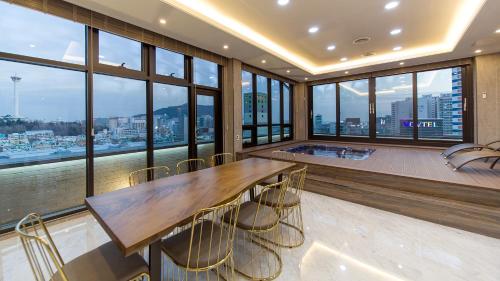 Habitación grande con mesa, sillas y ventanas. en GnB Hotel en Busan