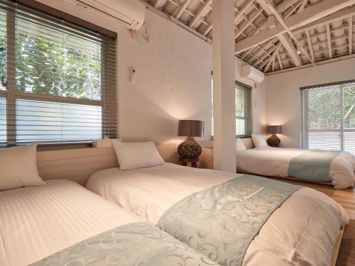 1 dormitorio con 2 camas y 2 ventanas en ADAN RESORT 太陽 - Tida -, en Bise