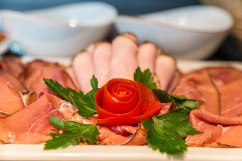 a plate of meat with a red rose on top at Hotel Haunstetter Hof Augsburg in Augsburg