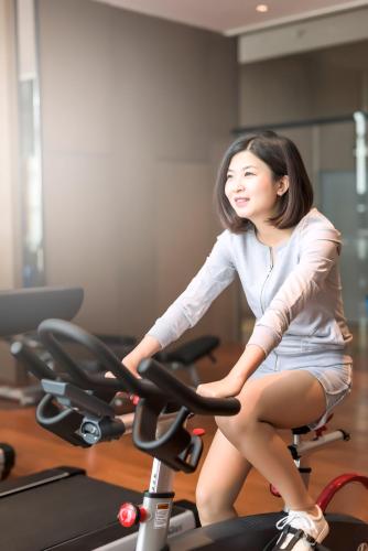a woman sitting on a exercise bike in a gym at Novotel Chennai OMR in Chennai