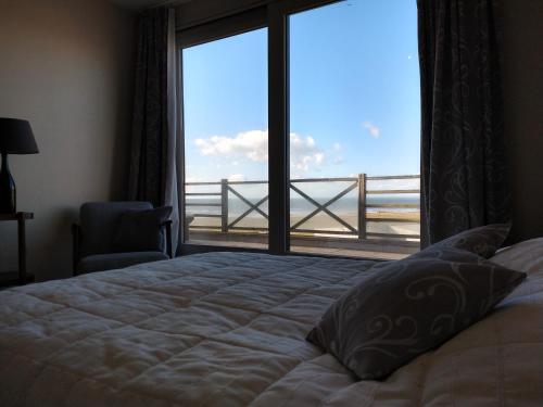 a bedroom with a bed and a window with a view at La Naturelle 119 in Wimereux