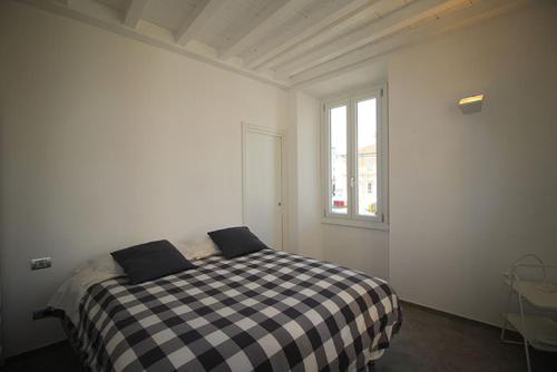 a white bedroom with a black and white checkered bed at Piazza Trento 11 in Monza